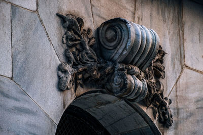 Low angle view of old statue against wall