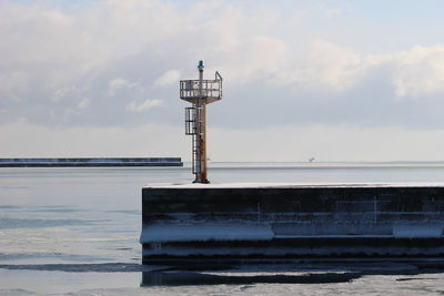 Lighthouse by sea against sky