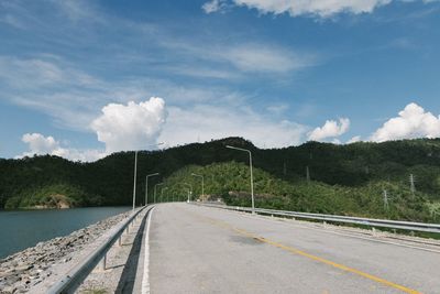 Road by trees against sky