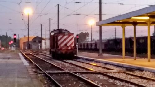 Train at railroad station against sky at sunset