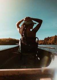 Woman sitting on boat in sea against sky