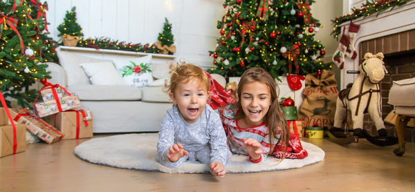 Portrait of siblings sitting on sofa at home