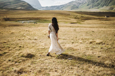 Young woman standing on field in the mountain landscape