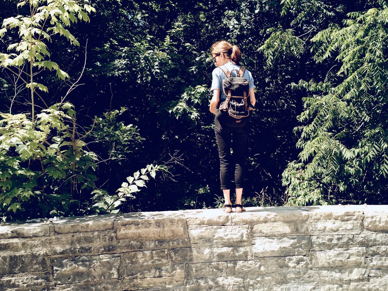 WOMAN STANDING ON TREE TRUNK