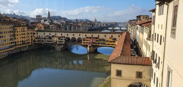 Arch bridge over river amidst buildings in city