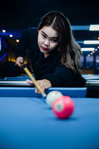 Portrait of young woman playing pool