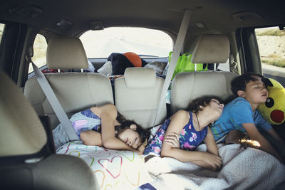 Tired siblings sleeping in car