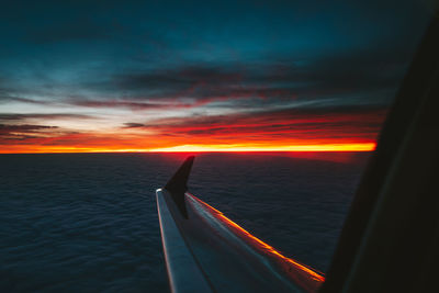 Airplane wing against sky during sunset