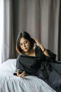 Young woman sitting on bed at home