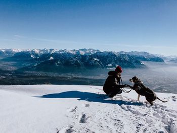 People with dog on snowcapped mountains during winter