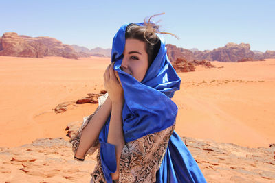 Young woman wearing sunglasses standing on sand dune