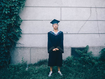 Full length of teenage girl standing against wall