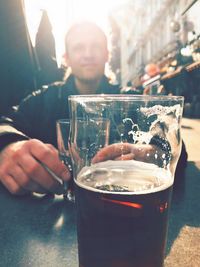 Close-up of beer glass on table against man
