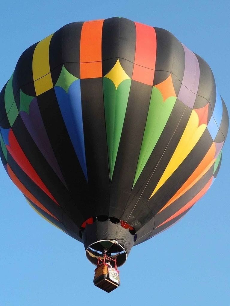 low angle view, hot air balloon, clear sky, mid-air, flying, multi colored, blue, sky, arts culture and entertainment, parachute, copy space, fun, adventure, amusement park, outdoors, ferris wheel, day, transportation, no people, air vehicle
