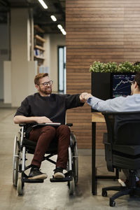 Happy disabled businessman greeting colleague in office