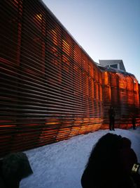 Rear view of people on snow covered against sky during sunset