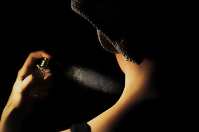 Close-up of woman holding glass over black background