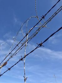 Low angle view of barbed wire against sky