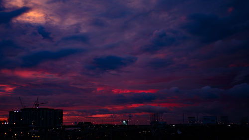 Silhouette buildings against dramatic sky at dusk