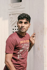 Portrait of young man standing by wall