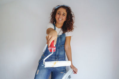 Portrait of smiling woman standing against wall