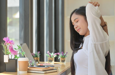 Woman standing by potted plant on table