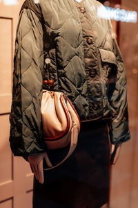 Fancy details of a green jacket with buttons and beige handbag. women's fashion clothing