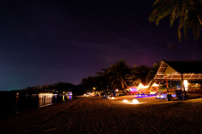 Illuminated beach against sky at night