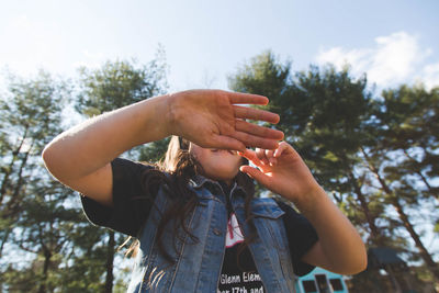 Low angle view of girl playing against trees at park on sunny day