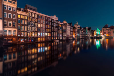 Canal amidst buildings at night