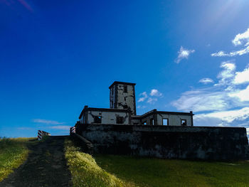 Abandoned house on field against blue sky