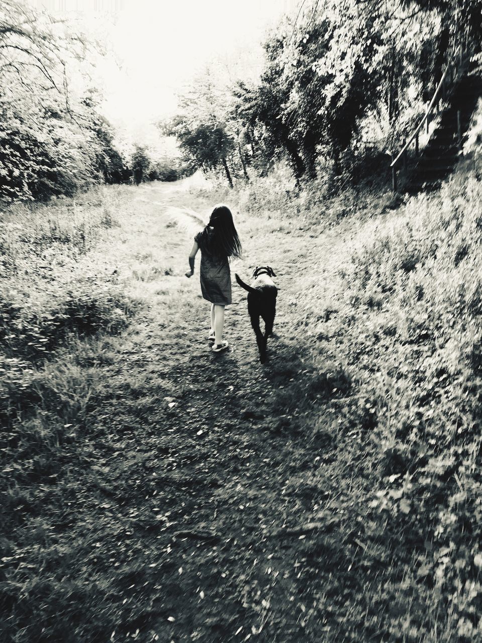 REAR VIEW OF A WOMAN WALKING ON THE ROAD