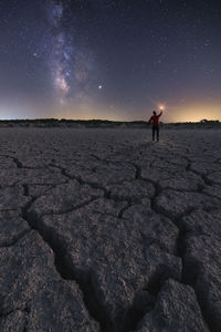 Man standing on rock against sky at night