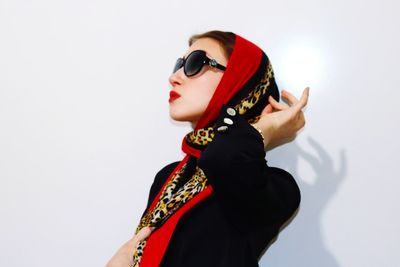 Side view of woman wearing sunglasses against white background