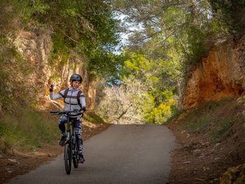 Man riding bicycle on road amidst trees