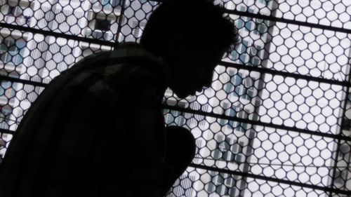 Close-up of silhouette man seen through chainlink fence