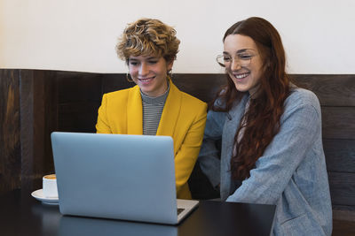 Smiling business colleagues using laptop in coffee shop