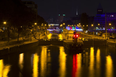 Illuminated bridge over river in city at night