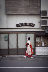 Full length of woman in traditional clothing walking on footpath against building