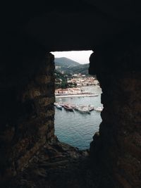 High angle view of boats moored on sea seen through hole stone wall
