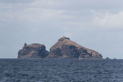 Rock formations by sea against sky