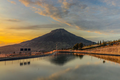 Scenic view of lake against cloudy sky during sunset