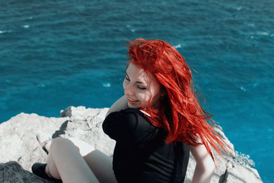 Beautiful young woman sitting at sea shore