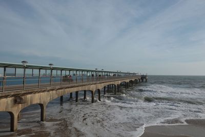 Pier on beach against sky