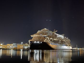 Illuminated ship by sea against sky at night