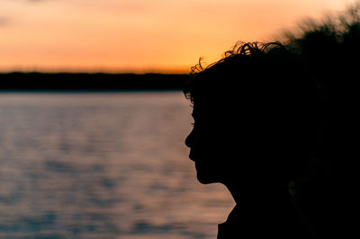 Close-up portrait of silhouette man against sea during sunset