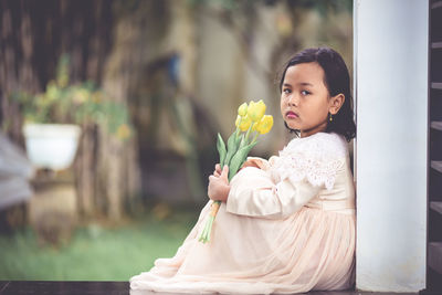 Cute girl looking away while standing by plant