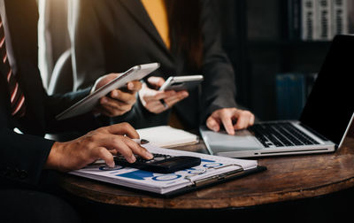 Business persons using calculator on table