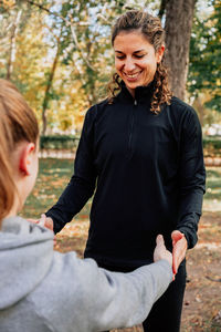 Smiling woman with arms raised while standing in autumn