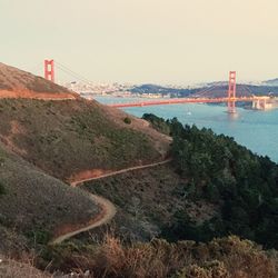 Suspension bridge over sea against clear sky
